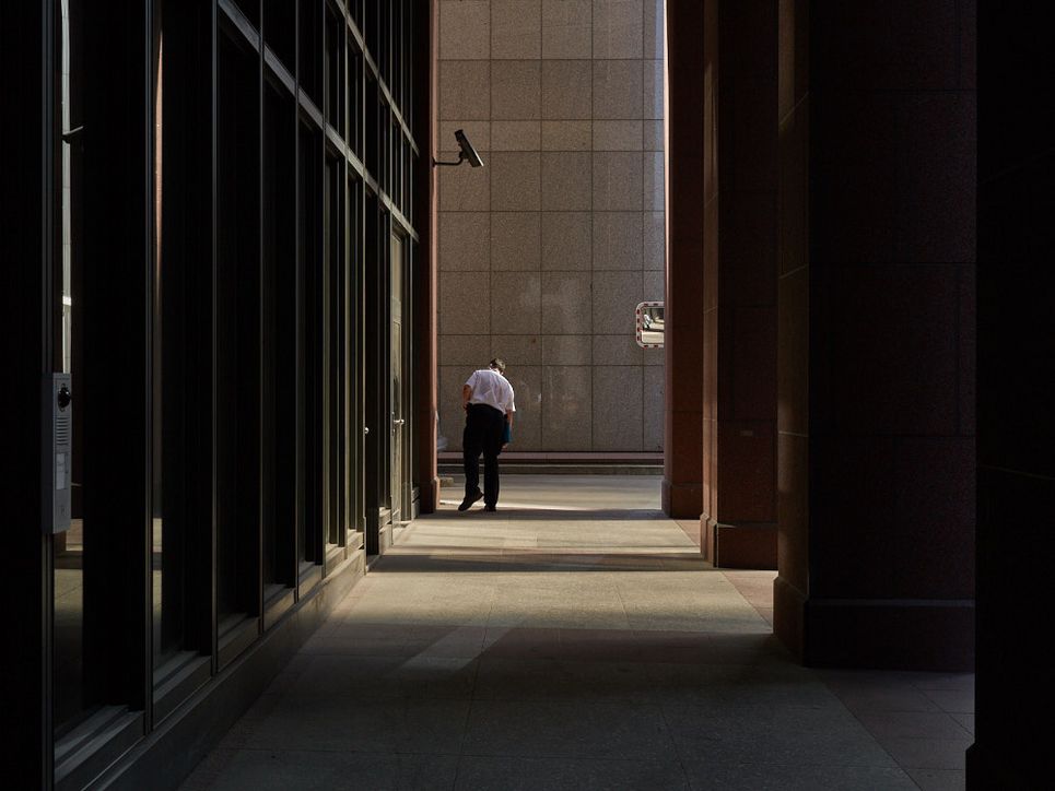 Ein Mann blickt um die Ecke am Ende eines Säulengangs.