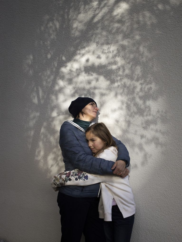 Eine Frau umarmt ein Mädchen, hinter ihnen Schattenspiele an der Wand.