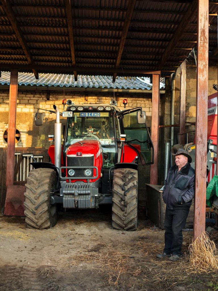 Eine Person vor einem Traktor, in dessen Frontscheibe Kennzeichen mit dem Name Bernd hängt.