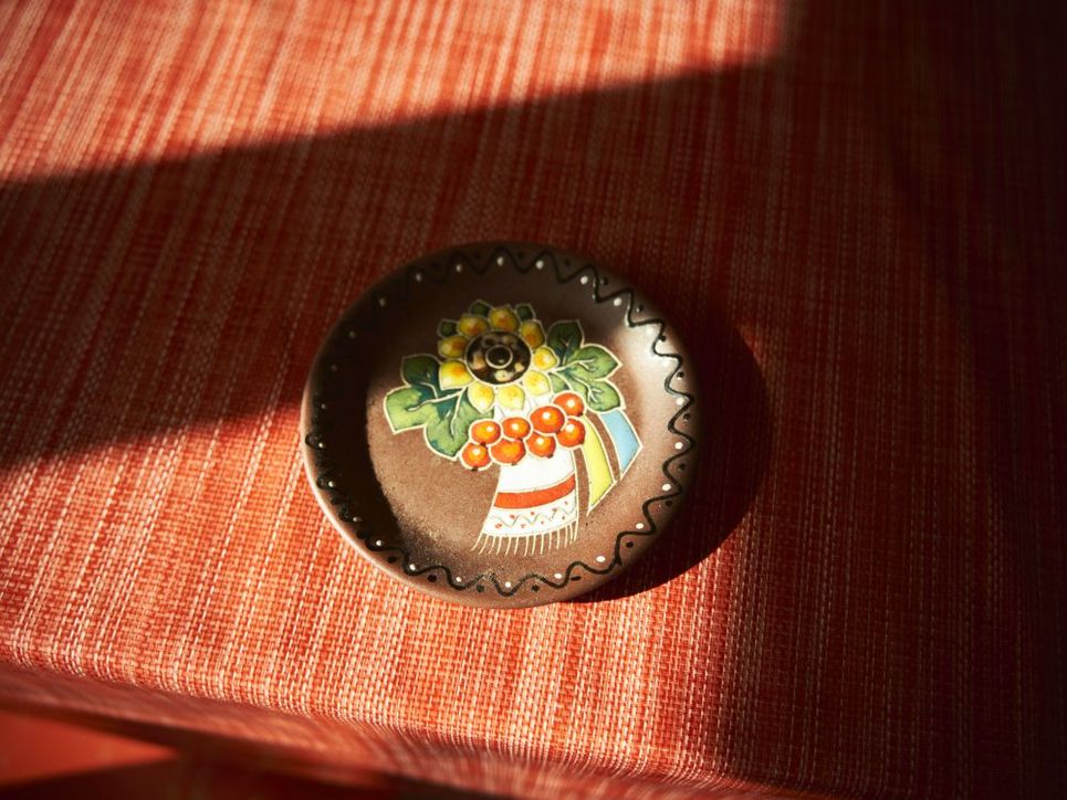 kleiner Teller mit aufgemalter Sonnenblume auf einem Tisch mit Tischdecke