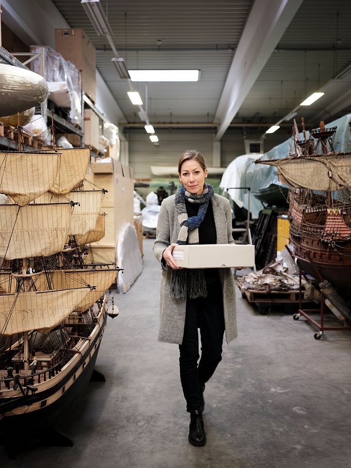 Kathrin Kleibl mit einem Karton zwischen Holzmodellen historischer Schiffe im Lagerraum des Schifffahrtsmuseums