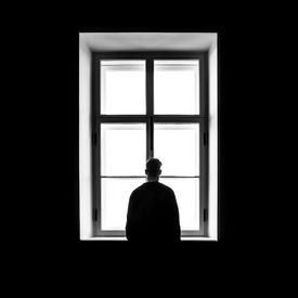 Eine Person steht vor einem Fenster.