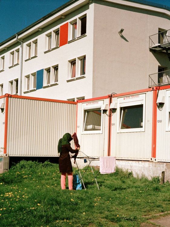Eine Frau hängt Wäsche auf vor Wohncontainern.
