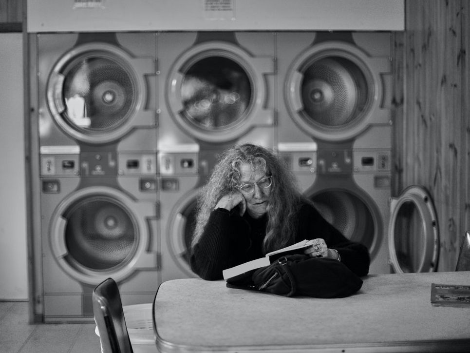Eine Frau, die in einem Waschsalon ein Buch liest.