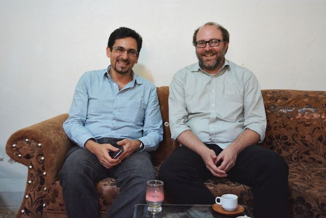 Zwei lachende Männer auf einem Sofa.