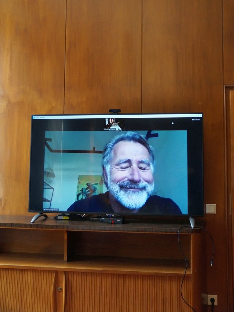 Porträt von Wolfgang Merkel per Video auf einem Bildschirm.