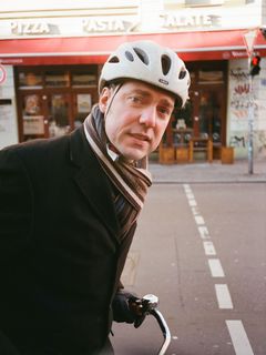 Hanno Hochmuth mit Fahrradhelm auf dem Fahrrad in der Berliner Innenstadt.