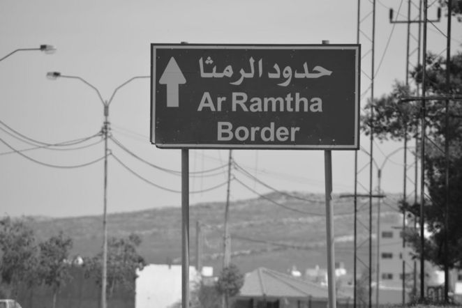 Straßenschild mit arabischer Schrift. Darunter die Aufschrift: Ar Ramtha, Border.