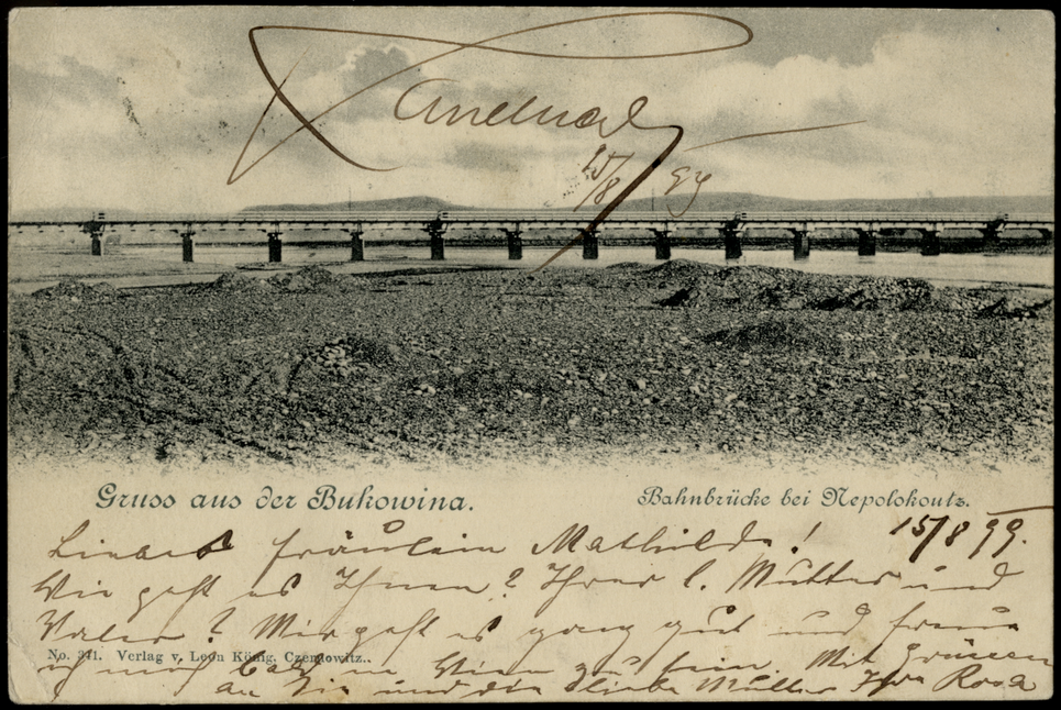 Handbeschriftete Postkarte, die eine Eisenbahnbrücke über einen Fluss zeigt und die Aufschrift »Gruss aus der Bukowina« trägt.