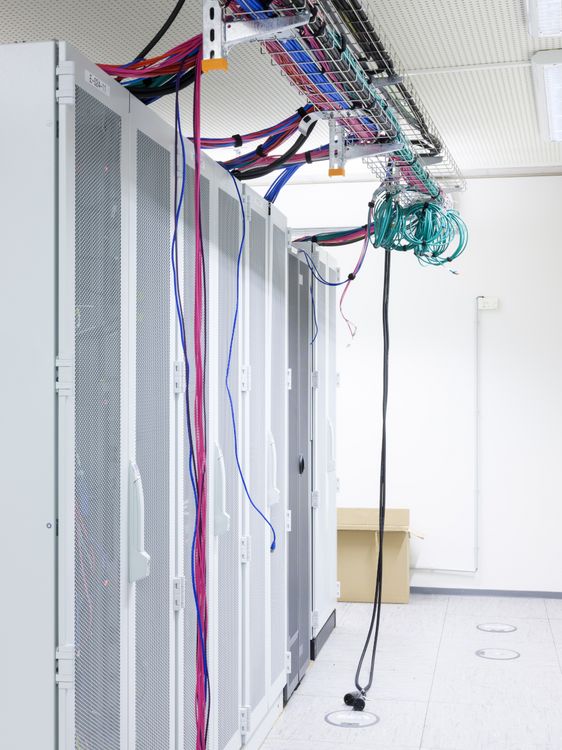 Raumhoher Server mit vielen Kabeln oben, die zum Teil herunterhängen.