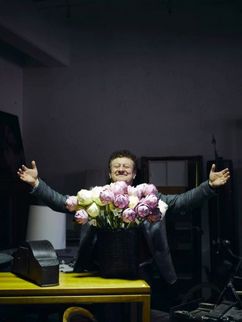 Wolfgang M. Heckl in einem dunklen Raum hinter einem erleuchteten Blumenstrauß.