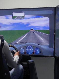 Eine Person im Fahrsimulator mit Blick auf eine virtuelle Landstraße.