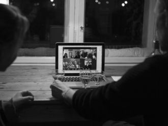 zwei Personen vor einem Laptop während einer Videokonferenz.