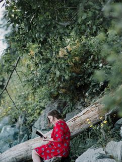 Lesende weiblich gelesene Person in der Natur.