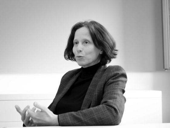 Barbara Sturm sitzt an einem Tisch, redet und gestikuliert mit den Händen auf dem Tisch. 