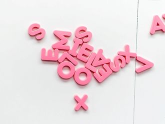 Verstreut herumliegende, pinke Buchstaben aus Plastik.