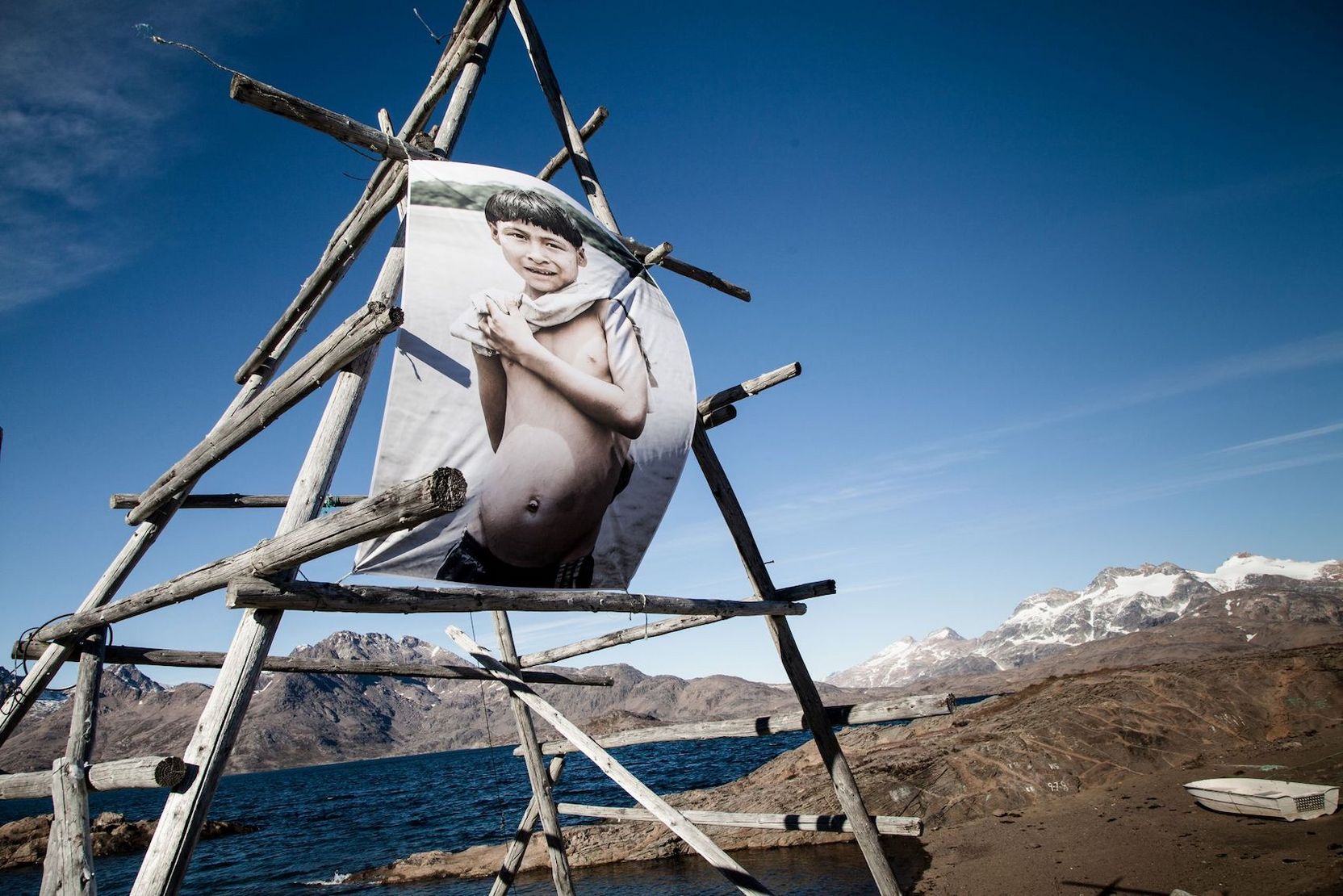 Bild eines Jungen in einer Gletscherregion, das an einem Hozgestell befestigt ist.