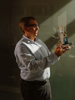 Porträt von Ramon Haindl, der eine Handprotese hält.
