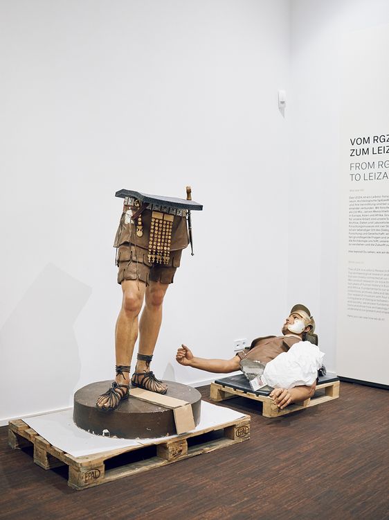 Archäologisches Ausstellungsstück: Stehende Beine eines Kriegers, dessen Oberkörper daneben auf dem Boden liegt.