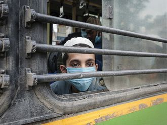 Junge mit OP-Maske schaut aus dem Fenster eines Zuges.