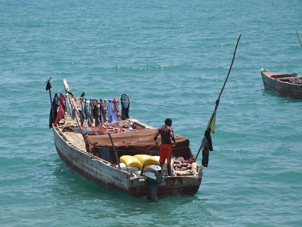 Beladenes Fischer-Motorboot, am Bug hängen Klamotten an einer Leine.