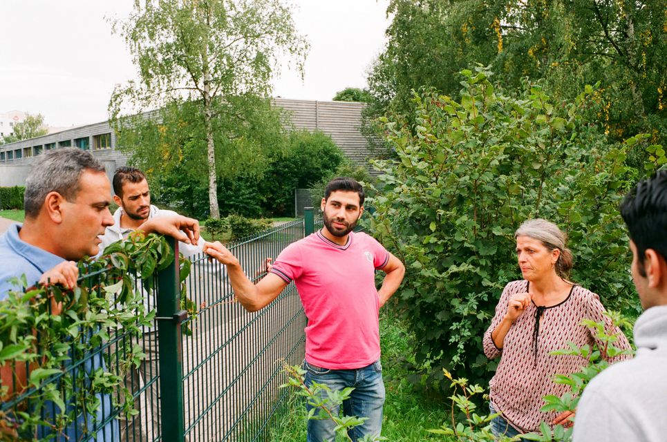 Fünf Personen unterhalten sich über einen Zaun hinweg.