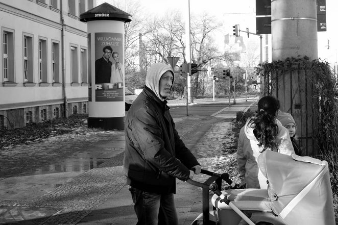 Junger Mann mit Kinderwagen und zwei Kinder in der Innenstadt.