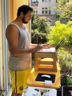 Ilyas Saliba arbeitet stehend am Laptop auf seinem Balkon.