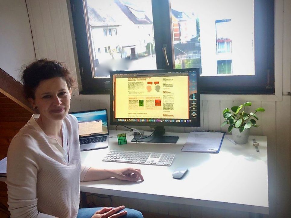 Annika Scholl am Schreibtisch, auf dem ein Laptop und ein größerer Bildschirm stehen.