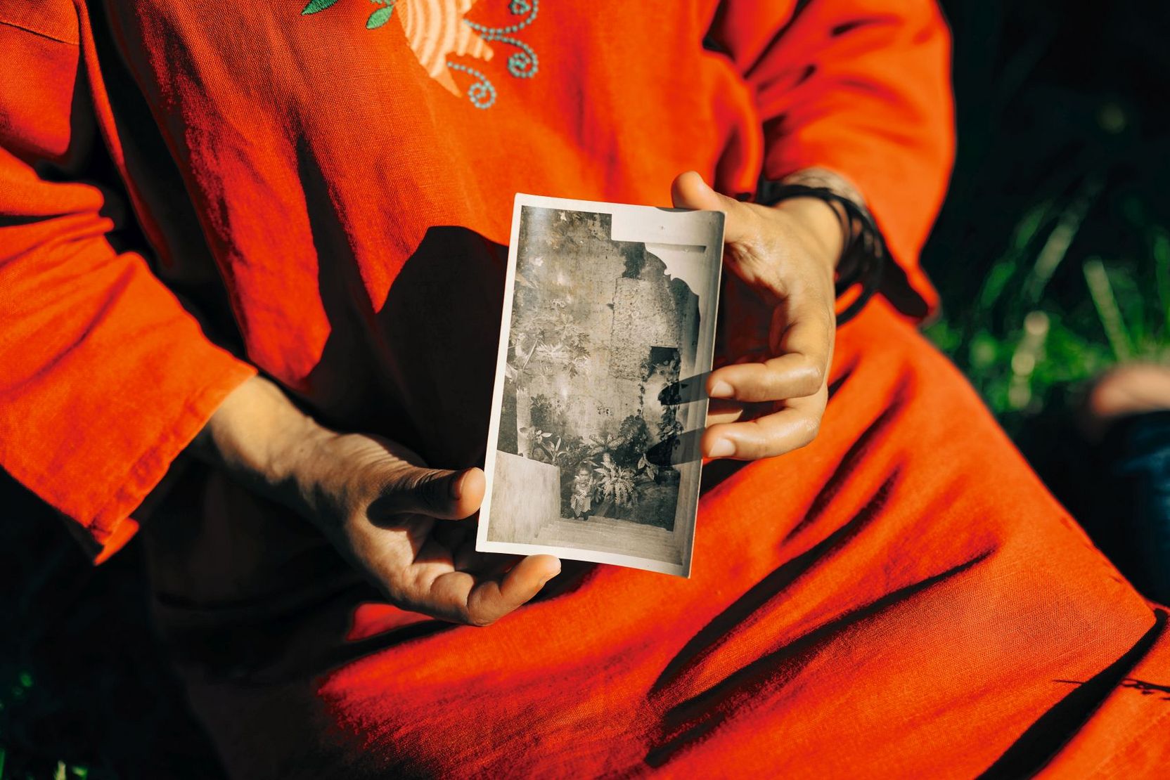 Eine Frau hält ein Schwarz-Weiß-Bild aus ihrer Kindheit in den Händen.