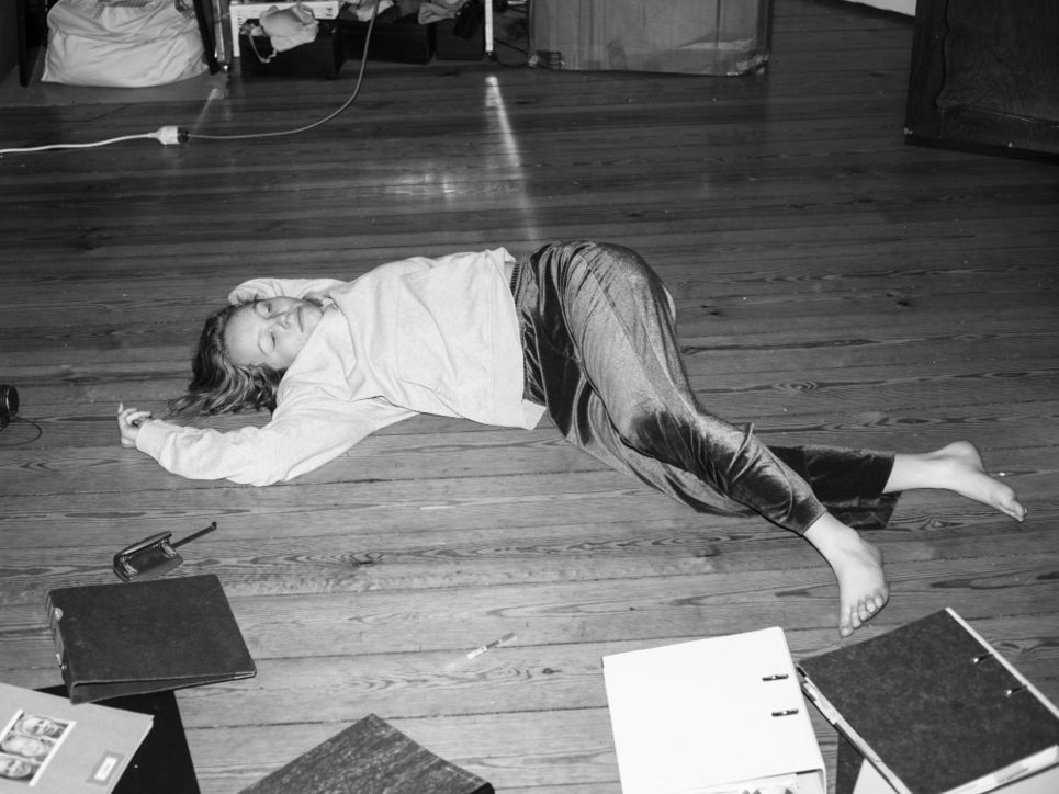 Ein Mädchen liegt auf dem Fußboden, vor ihr liegen Ordner.