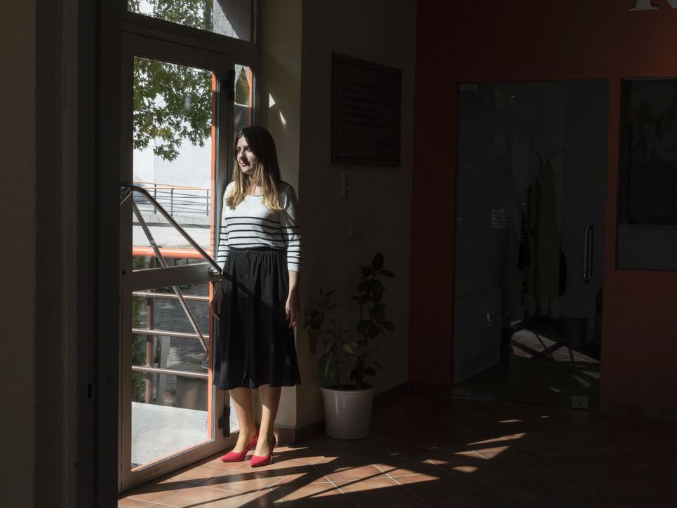 Eine junge Frau steht am Fenster, durch das Sonnenlicht in den Raum fällt.
