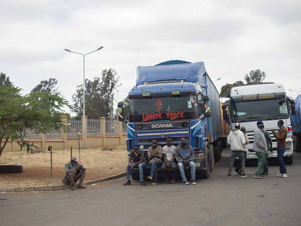 Mehrere Fahrer warten auf der Stoßstange eines Lastwagens auf die Testergebnisse.