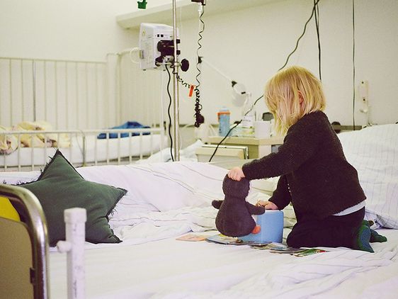 Kleines blondes Mädchen spielt auf einem Krankenhausbett