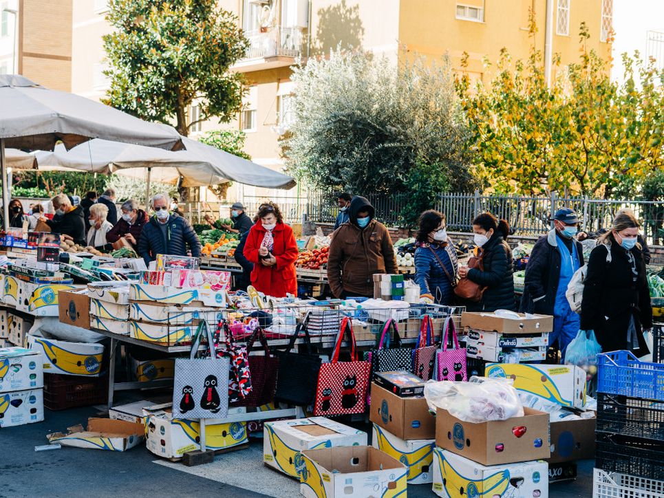 Personen mit medizinischen Masken auf einem Wochenmarkt.