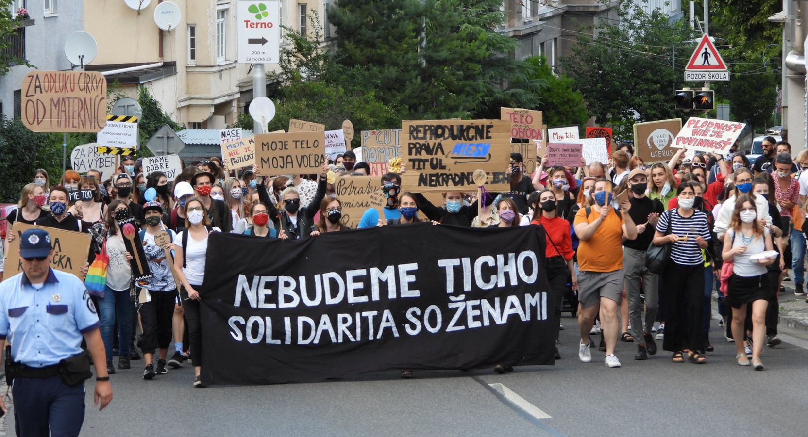 Die Demonstrierenden auf der Straße, das schwarze Banner mit der Aufschrift »Nebudeme Ticho!« – »Wir werden nicht schweigen!« wird ganz vorne getragen.
