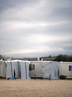 Weiße Wohncontainer einer Unterkunft für Geflüchtete, in ländlicher Umgebung