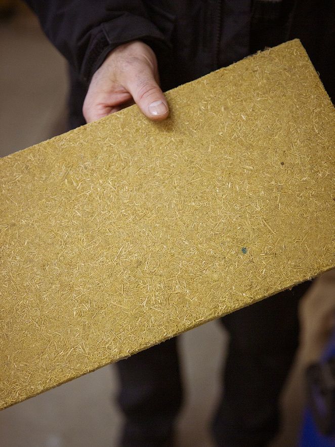 Ralf Pecenka zeigt eine Holzplatte aus gepresstem Holz 