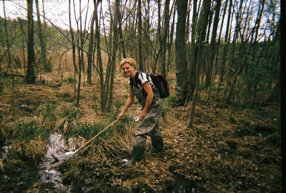 Doreen Werner schöpft Wasser aus einem kleinen Bach im Wald.