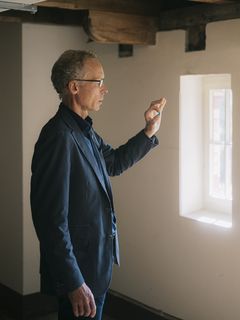 Johan Rockström hält eine kleine blaue Kugel zwischen zwei Fingern gegen das Licht.