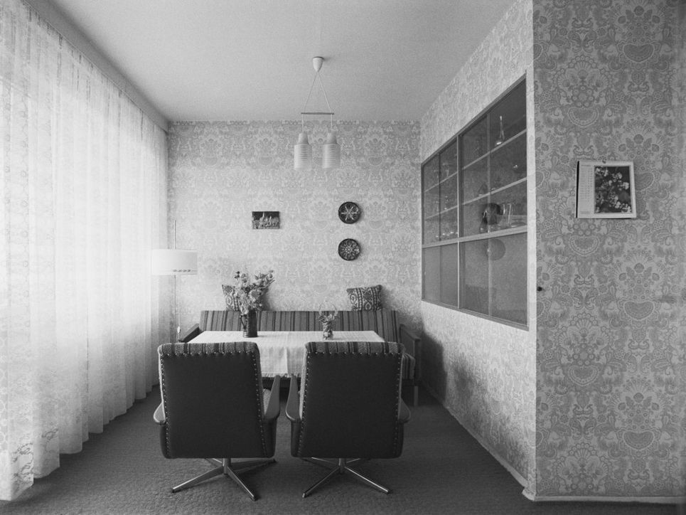Tisch mit Sesseln und Sitzbank und einer Stehlampe im Wohnzimmer des Wohnungstyps P2.