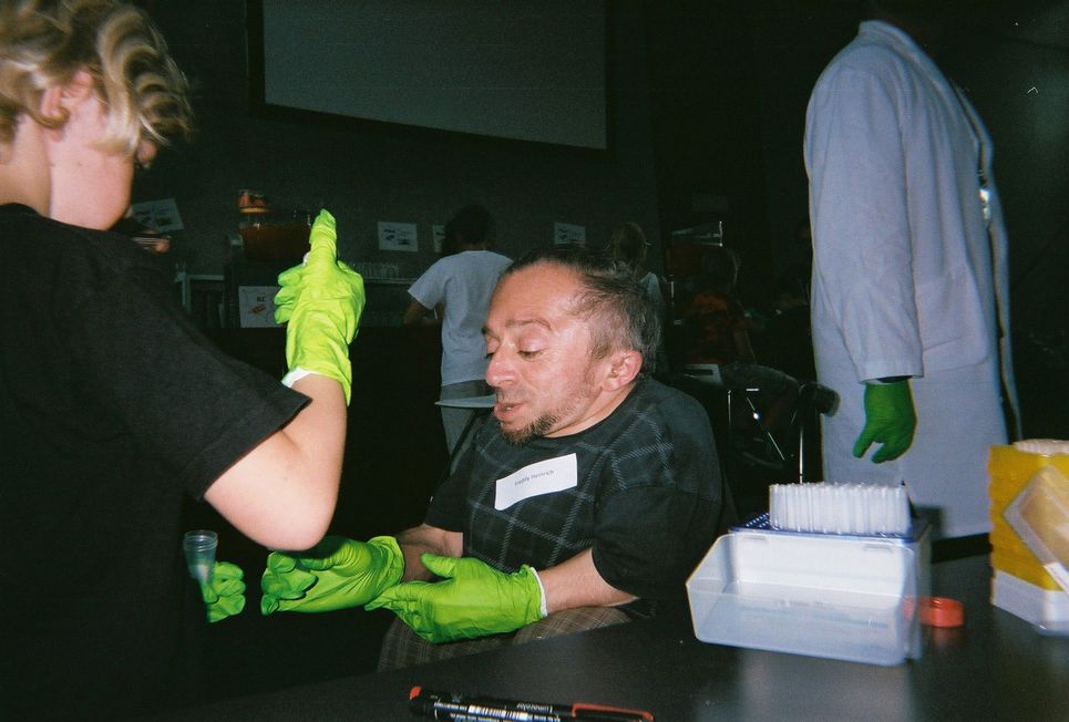 Frederik Heinrich im Labor mit Giftgrünen Handschuhen beim Hantieren mit Reagenzgläsern