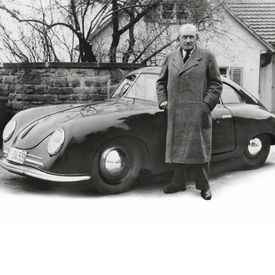 Historische Aufnahme von Ferdinand Porsche vor einem Porsche.