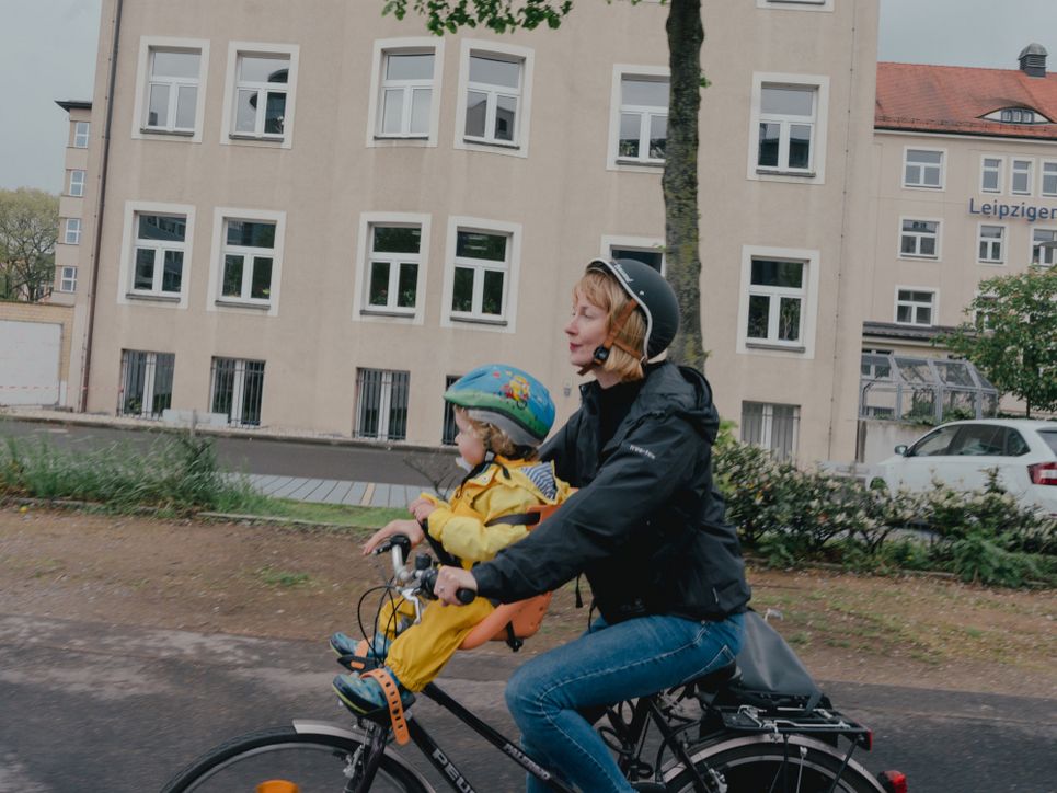 Liina Tõnisson fährt mit ihrer Tochter auf dem Fahrrad durch eine Leipziger Wohngegend.