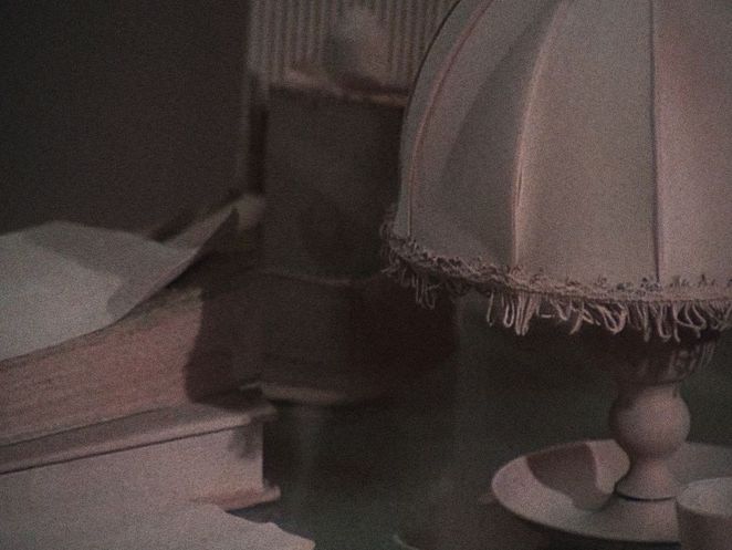 Ein Stillleben, auf dem links unten zwei Bücher gestapelt liegen. Rechts im Bild sieht man eine Lampe mit Lampenschirm.