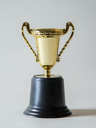 Goldener Pokal auf schwarzem Sockel.