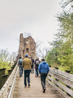 Mehrere Personen gehen bergauf zu einer Ruine.