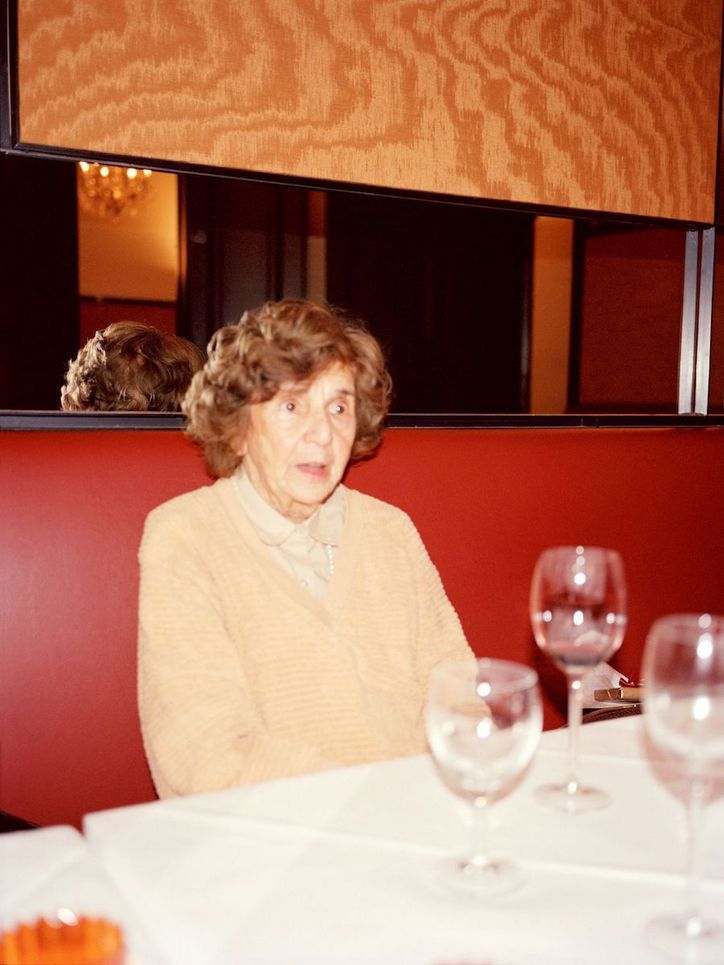 Eine alte Frau im Restaurant, vor ihr leere Weingläser auf dem Tisch.