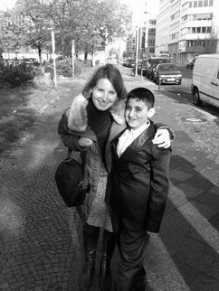 Susanne Hörr mit Ahmad auf einem Bürgersteig in Berlin. Sie beugt sich zu ihm herunter und legt ihren Arm um seine Schulter.
