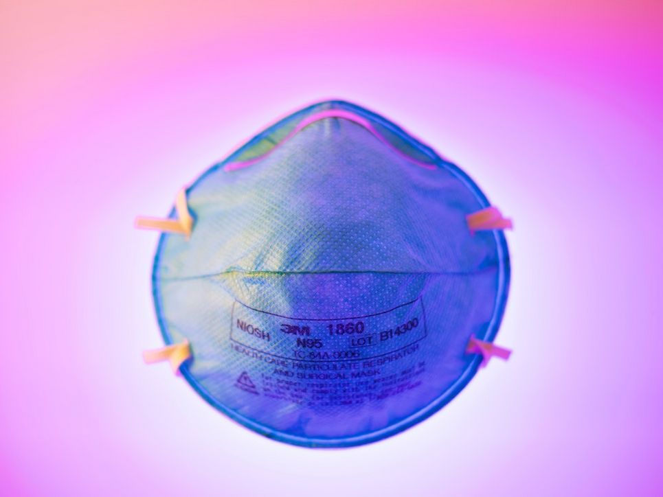 Blaue medizinische Maske vor violettem Hintergrund.